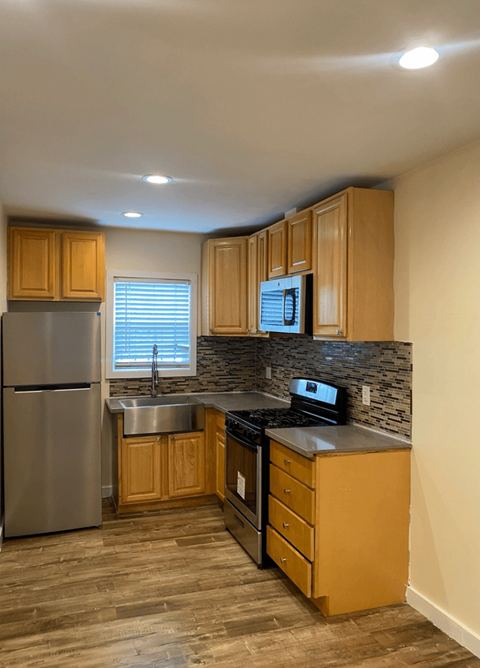 A kitchen with wooden cabinets and a stainless steel refrigerator.
