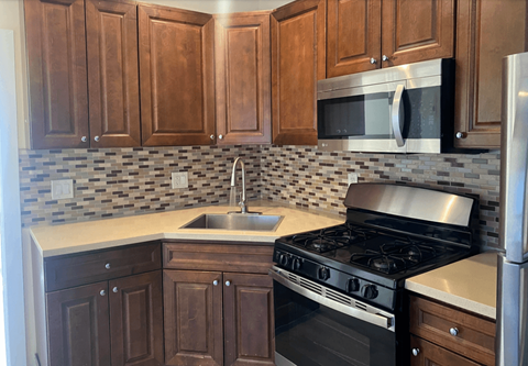 A kitchen with a black stove and wooden cabinets.
