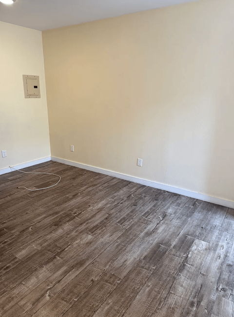 A room with wooden flooring and a white wall.