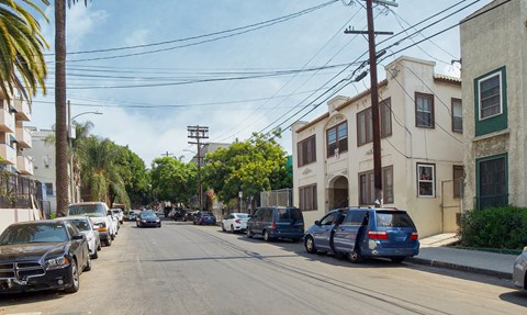 A street with cars parked on both sides and a few moving cars.
