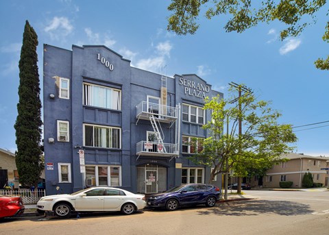 A blue building with the number 1000 on it and the words "Serrano Plaza" above the entrance.