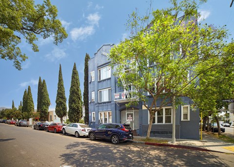Cars parked on a street in front of a blue building.