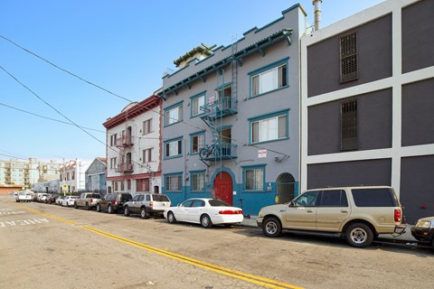 A row of cars parked on a street in front of a building.