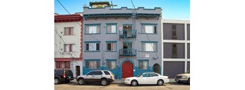 A white car is parked in front of a blue building.