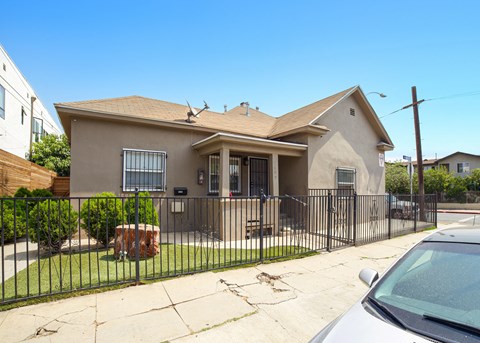 A house with a brown roof and a white car parked in front.