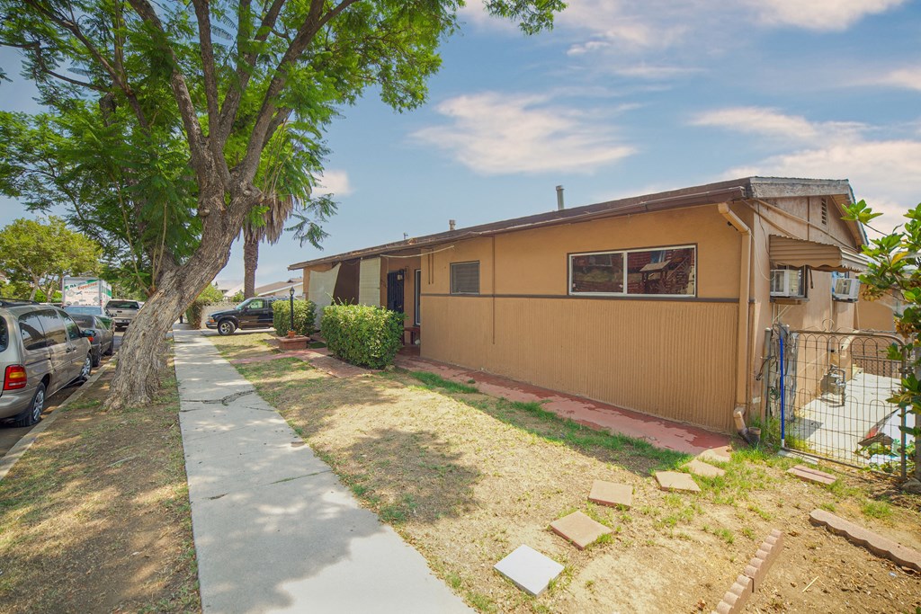 A house with a brown exterior is surrounded by a fence and a tree.