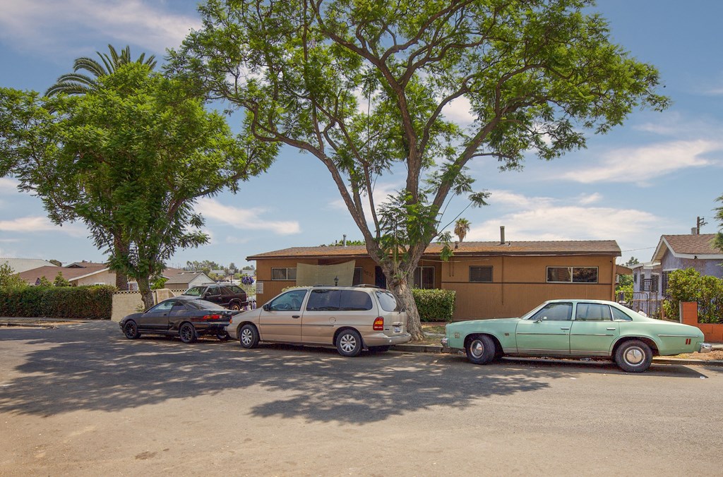 Three cars parked in a driveway in front of a house.