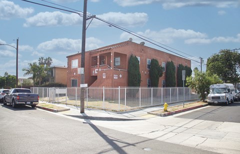 A red brick building with a white fence in front of it.