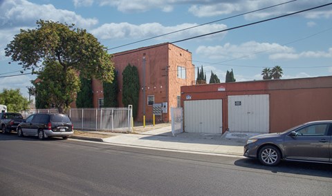 A street view with cars parked on the side and a building in the background.