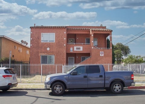 A silver truck is parked in front of a red building.