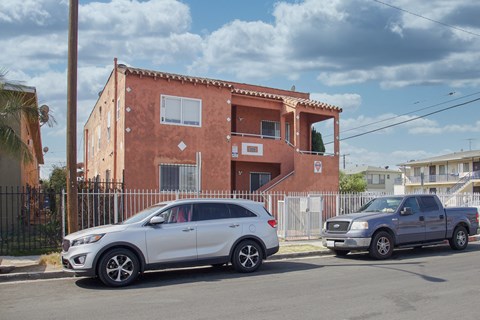 A white car is parked in front of a red building.