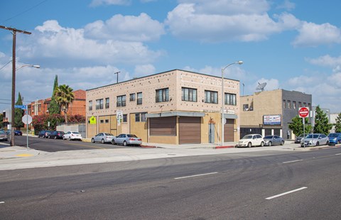 A street view of a building with cars parked in front.