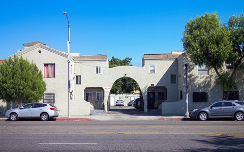 A white building with a red door and a car parked in front.