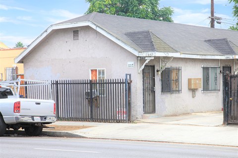 A white truck is parked in front of a house with a black fence.