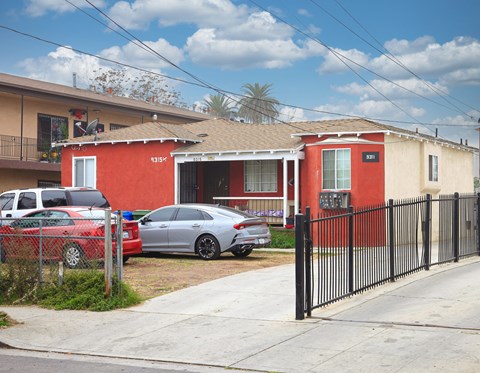 a house with a fence and cars parked in front of it