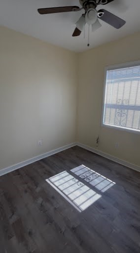 A room with a ceiling fan and a window with blinds.