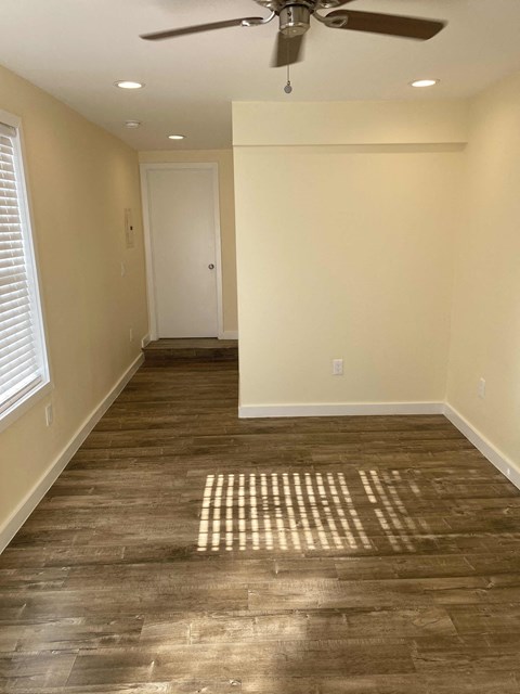 A room with a ceiling fan and wooden flooring.