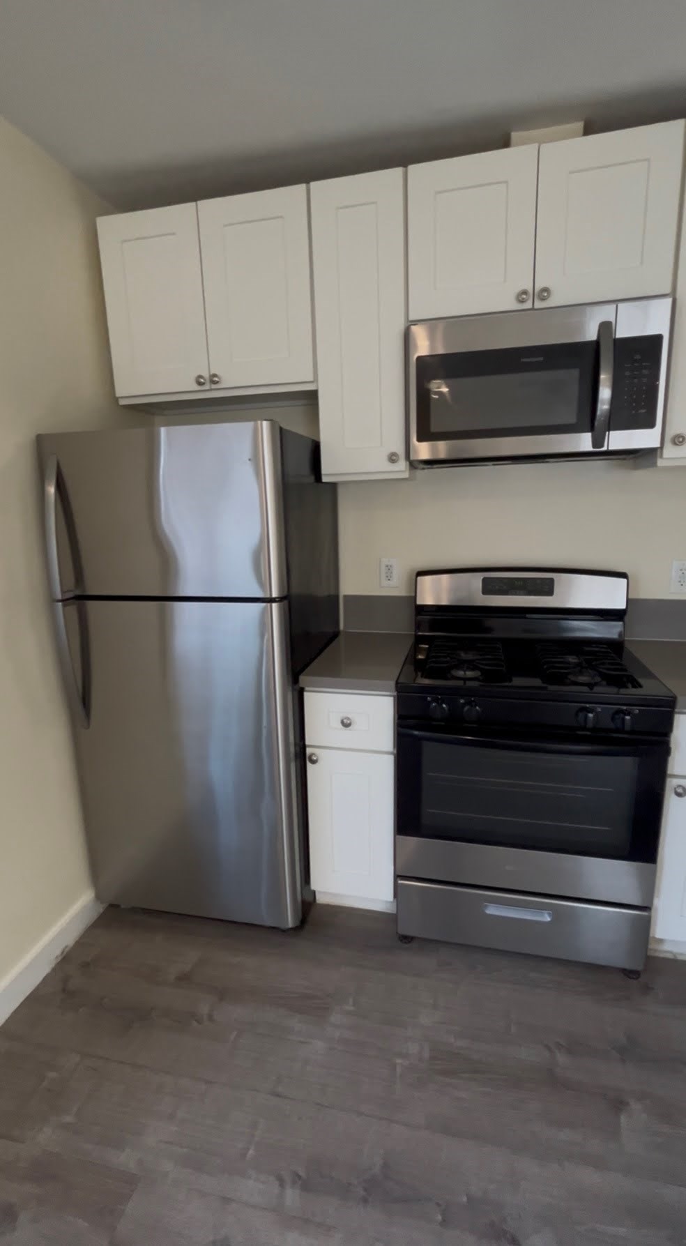 A kitchen with a stainless steel refrigerator, microwave, and stove.