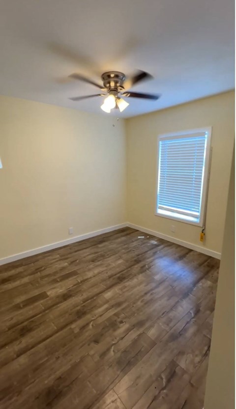 A room with a ceiling fan and wooden flooring.