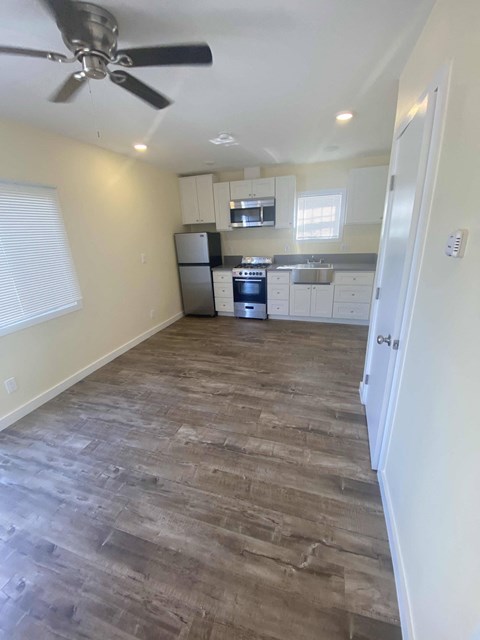 A kitchen with a fan on the ceiling and wooden flooring.