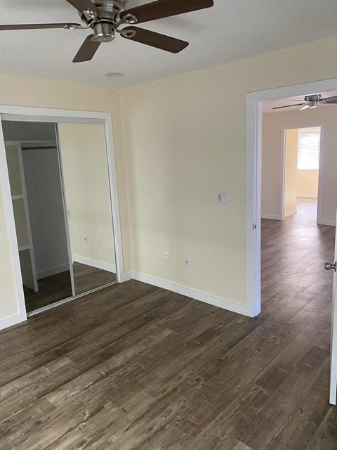 A room with a ceiling fan and wooden flooring.
