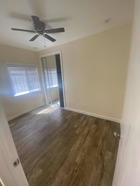 A room with a ceiling fan and wooden flooring.