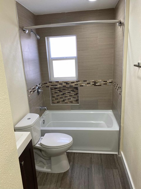 A white toilet sits next to a bathtub in a bathroom.