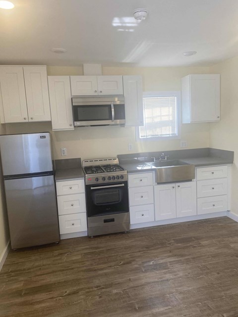 A kitchen with a stainless steel refrigerator, oven, and microwave.