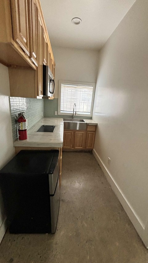 A kitchen with a black fridge and wooden cabinets.