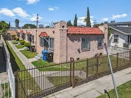 A house with a red roof is surrounded by a black fence.