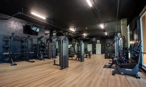 A gym with a variety of equipment including treadmills, weights, and exercise machines.