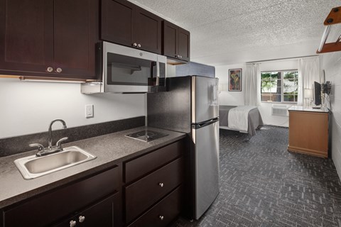 a kitchen in a hotel room with a sink and refrigerator