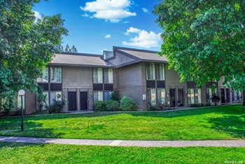 Large shade trees and an expansive lawn provide a lovely green space outside of Torrey Ridge Apartments. - Photo Gallery 2