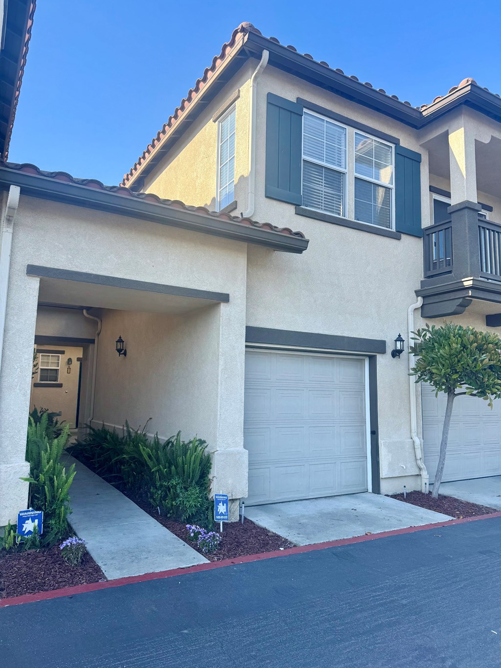 A house with a garage door and a tree in front.