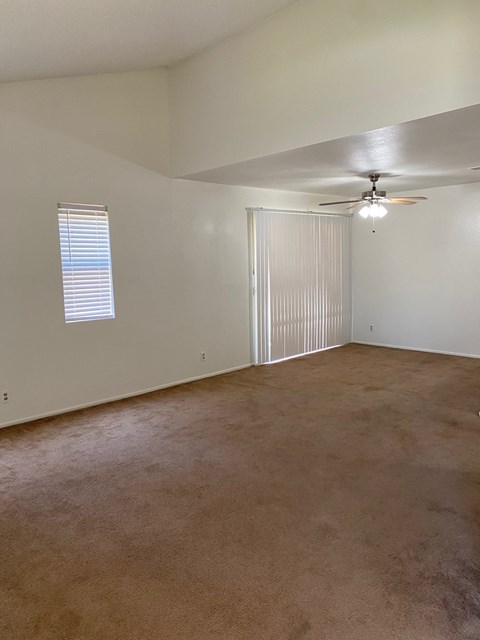 the living room of an empty house with a ceiling fan