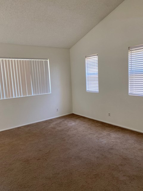 an empty living room with two windows and a carpet