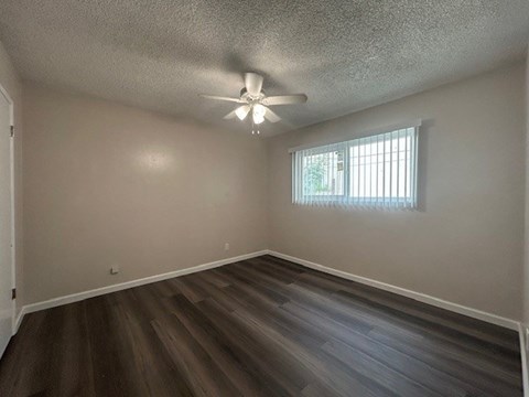 A room with a ceiling fan and a window with blinds.