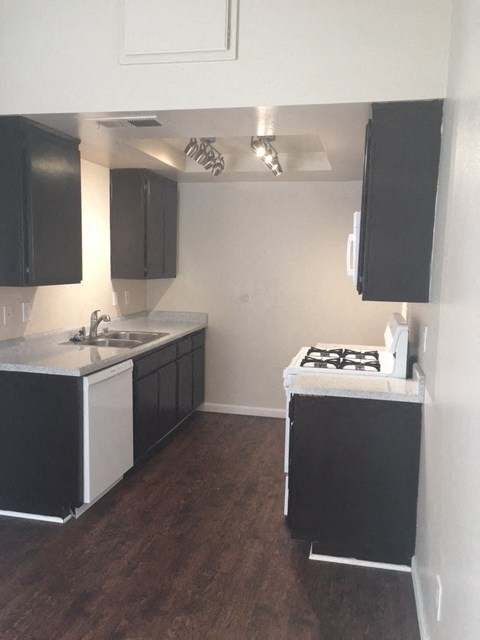A kitchen with black cabinets and a white sink.
