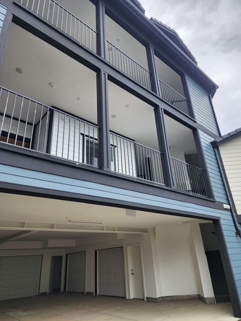 A modern building with a balcony and garage doors.