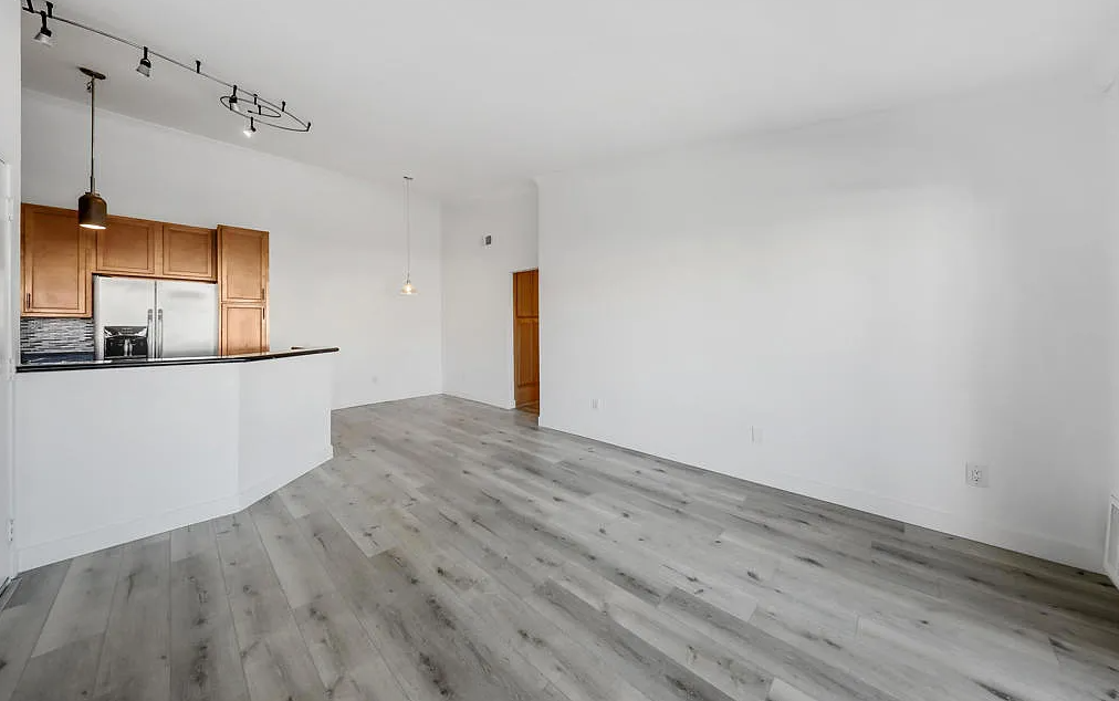 a kitchen and living room with white walls and wood floors