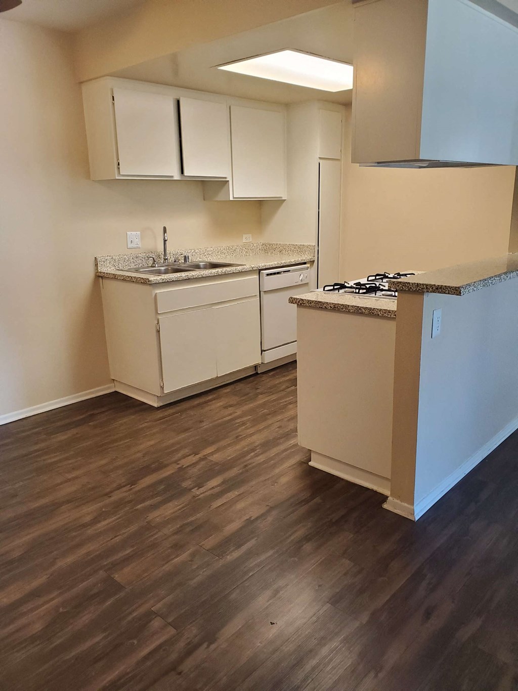a kitchen with white cabinets and a wood floor