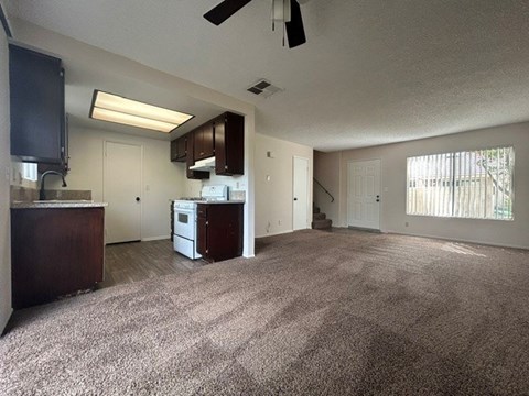A spacious living room with a kitchen area in the background.