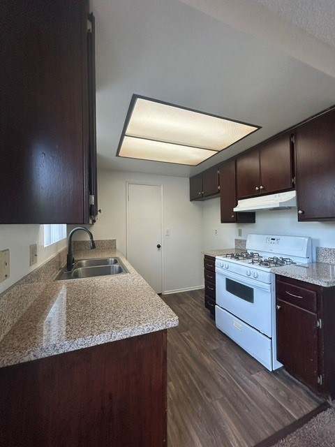 A kitchen with a sink, stove, and cabinets.