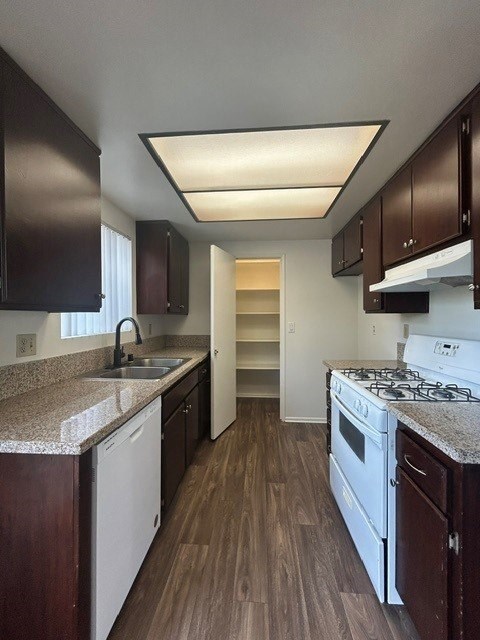 A kitchen with dark brown cabinets and a white stove top oven.