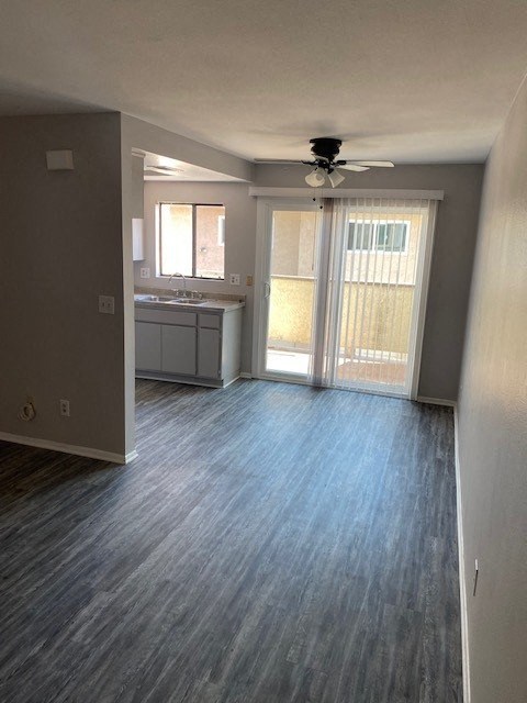 an empty living room with a ceiling fan and a kitchen