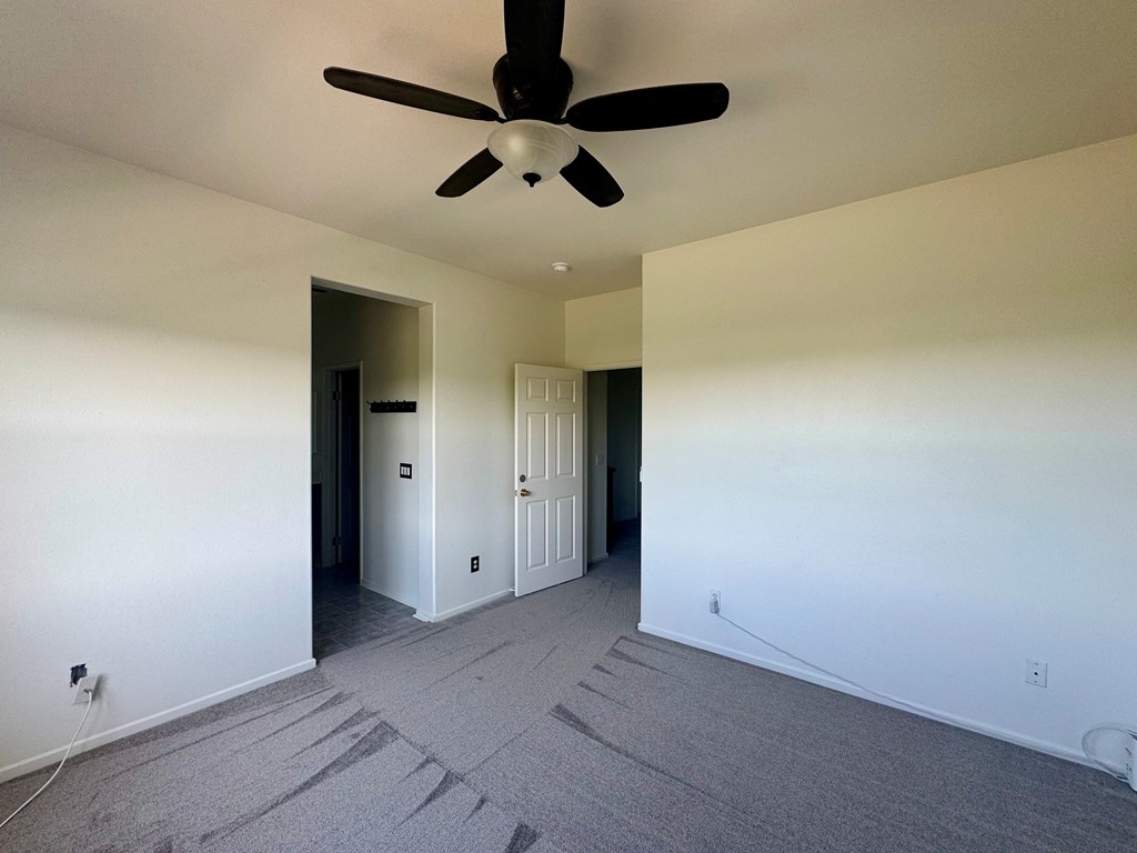 A room with a ceiling fan and carpeted floor.