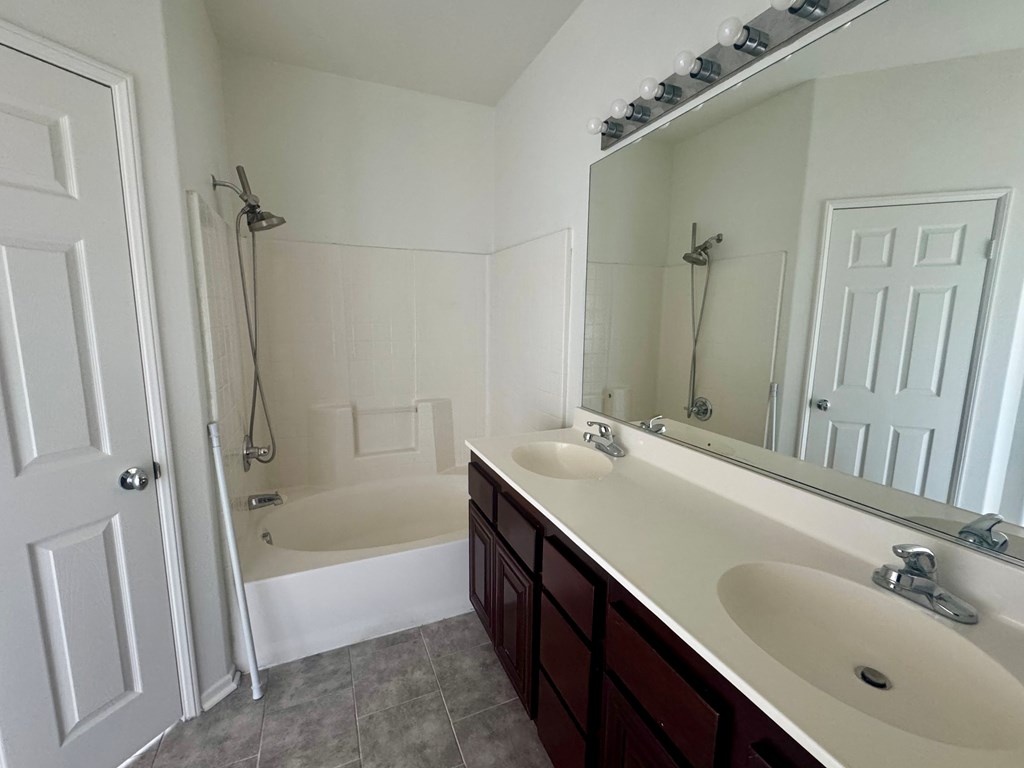 A white bathroom with a double sink and a bathtub.