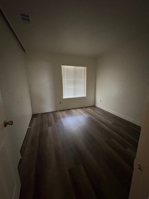 A room with wooden floors and a window with blinds.