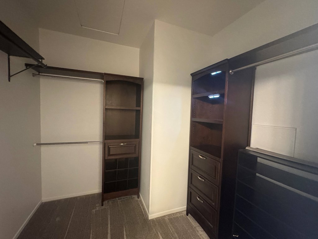 A room with a white door, a brown shelf, and a black dresser.