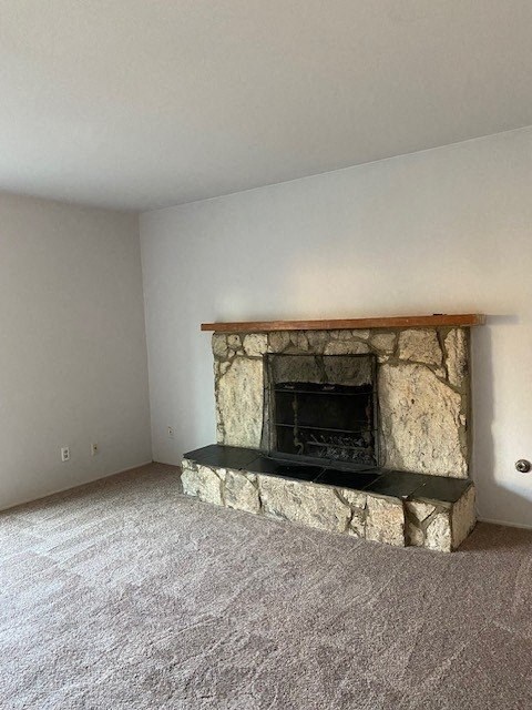 an empty living room with a stone fireplace